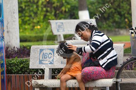 Vietnamese woman checking her childs hair for lice in Ho Chi Minh City, Vietnam.