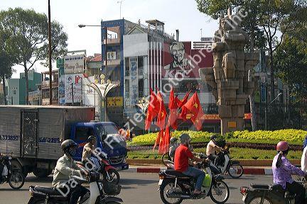 Vietnamese people ride motorbikes past Kentucky Fried Chicken sign and communist flags in Ho Chi Minh City, Vietnam.