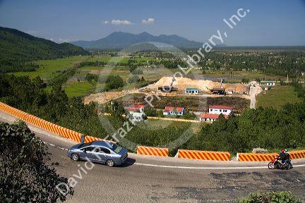 Automobile traveling on a road past a paper mill at Phu Gia, Vietnam.