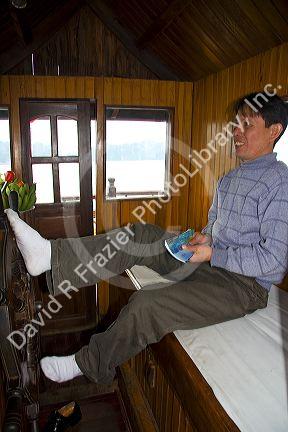Vietnamese boat captin steering with his feet in Ha Long Bay, Vietnam.