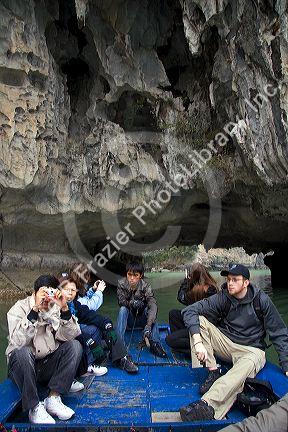 Tourists ride on a small boat viewing sea caves in Ha Long Bay, Vietnam.