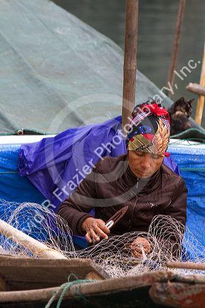 Vietnamese man repairing fishing nets in Ha Long Bay, Vietnam.