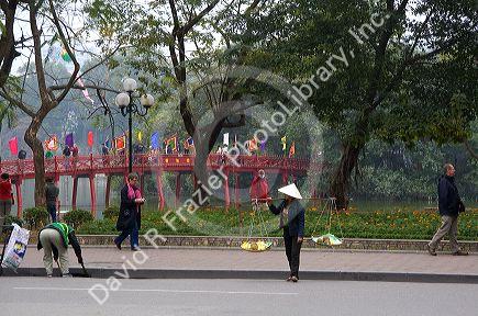 Street vendor in front of the Huc Bridge on Hoan Kiem Lake in Hanoi, Vietnam.