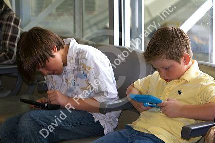Boys playing with a personal video game system at the Boise Airport, Idaho, USA. MR