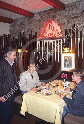 Owner chats with diners as they eat pasta in an Italian restaurant in Italy.