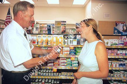 Woman consulting pharmacist about vitamins in a supermarket pharmacy.
