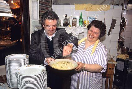 An Italian couple prepare a pasta dish at their restaurant in Italy.