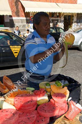 Street vendor carving and selling melon in the city of Puebla, Puebla, Mexico.