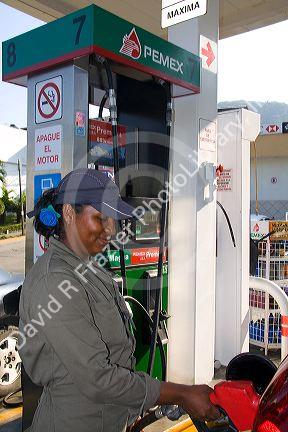 Mexican female attendant pumping fuel at a full service gas station in Acapulco, Guerrero, Mexico.