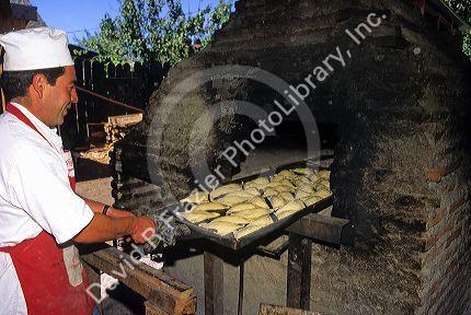 Chilean man cooking empanadas in a brick oven in Sanitiago, Chile.