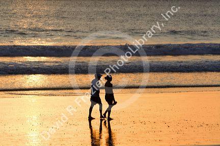 People walk on the beach at sunset in Jaco, Costa Rica.