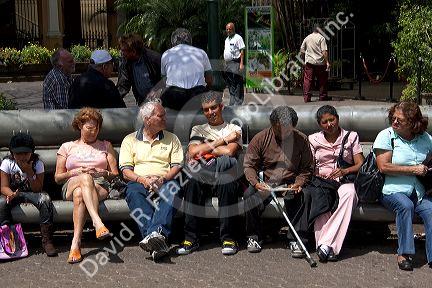 People sit on park benches in the city of San Jose, Costa Rica.