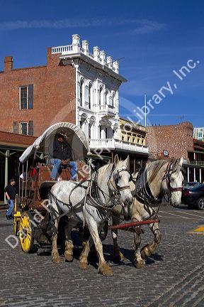 Tourists ride in a horse drawn covered wagon at Old Sacramento State Historic Park in Sacramento, Califorina, USA.