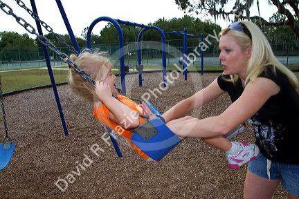 Mother pushing her 3 year old daughter in a swing, Brandon, Florida, USA. MR