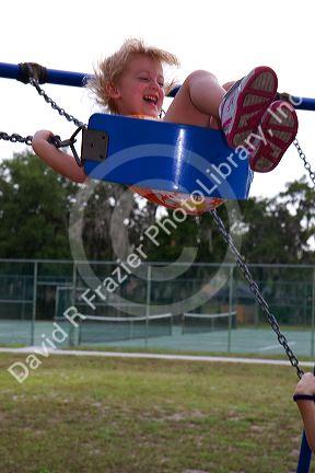 3 year old girl swinging on a swingset in Brandon, Florida, USA. MR