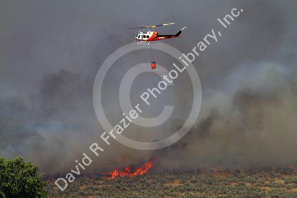Helicopter with water bucket performing aerial firefighting on a wildfire in Eagle, Idaho, USA.