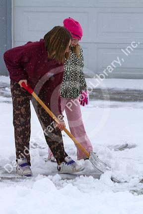 People shovel winter snow off of a driveway in Boise, Idaho, USA.