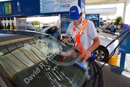Gas station attendent washing an automobile windshield in Argentina.