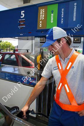 Gas station attendent fueling an automobile in Argentina.