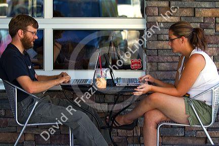 Modern couple using laptop personal computers at a coffee shop in Boise, Idaho, USA.