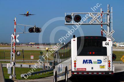 Boeing 737 at take off and a bus stopped at a railroad crossing at the Miami International Airport, Florida, USA.