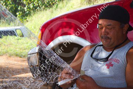 Native hawaiian fisherman mending a net on the island of Kauai, Hawaii, USA. MR