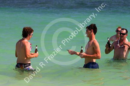 People drink bottled beer in the Gulf of Thailand at Chaweng beach on the island of Ko Samui, Thailand.