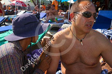 Man receiving a traditional tattoo at Chaweng beach on the island of Ko Samui, Thailand.