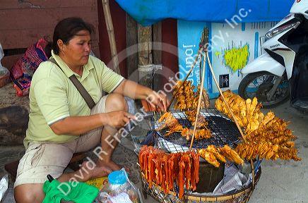 Food vendor grilling meat over a charcoal fire at Chaweng beach on the island of Ko Samui, Thailand.