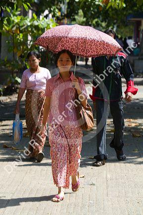 Burmese woman walking under the shade of an umbrella in (Rangoon) Yangon, (Burma) Myanmar.