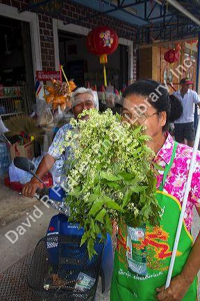 Grocer smelling fresh bay leaves being offered for sale by the grower on the island of Ko Samui, Thailand.