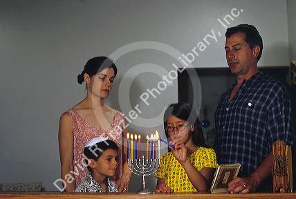 A jewish family lighting a menorah.  MR