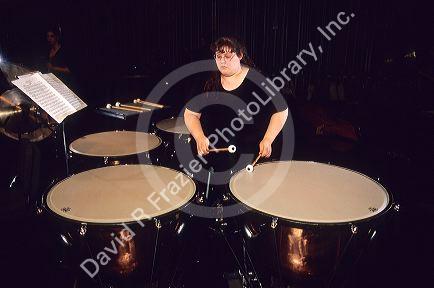 A woman plays a timpani.