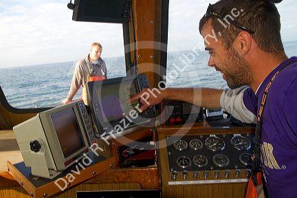 Fishing boat skipper checks the GPS receiver on a fishing boat in the Pacific Ocean off the coast of Westport, Washington, USA.