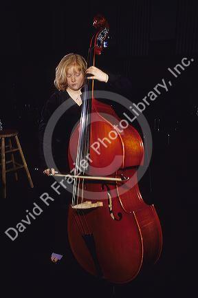 A girl plays an upright bass with a bow.