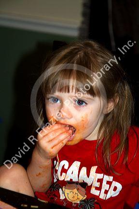 Two year old girl eating spaghetti and getting it all over her face, Tampa, Florida, USA.