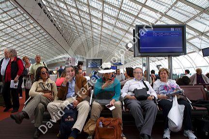 Travelers in a waiting room at Charles de Gaulle Airport, Paris, France.