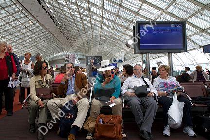 Travelers in a waiting room at Charles de Gaulle Airport, Paris, France.