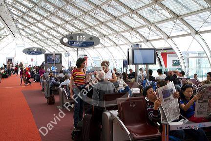 Travelers in a waiting room at Charles de Gaulle Airport, Paris, France.