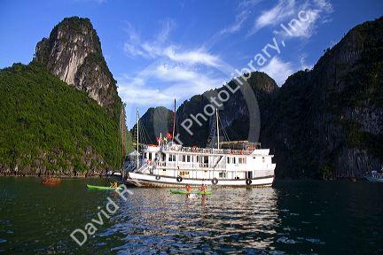 Tour boat and tourists using sea kayaks in Ha Long Bay, Vietnam.