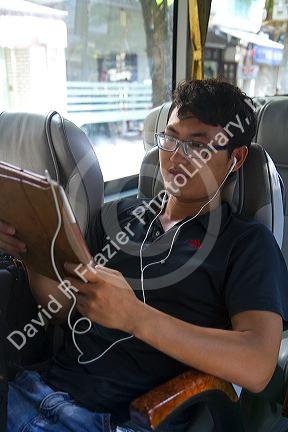 Young vietnamese man using a tablet computer on a bus in Hanoi, Vietnam.