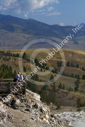 Tourists stand at a scenic overlook near Mammoth Hot Springs in Yellowstone National Park, Wyoming, USA.