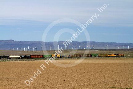 Union Pacific Railroad train traveling past a line of wind powered electric generators in Elmore County, Idaho, USA.