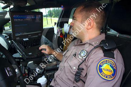 Florida state trooper using computer in patrol car.