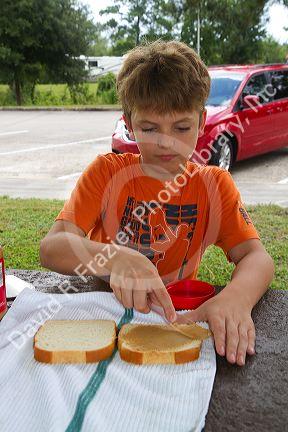 Ten year old boy making a peanut butter sandwich.