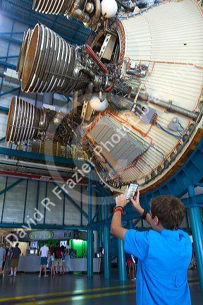 Boy taking a photo on his cellphone of the Saturn Rocket at John F. Kennedy Space Center, Merritt Island, Florida, USA.