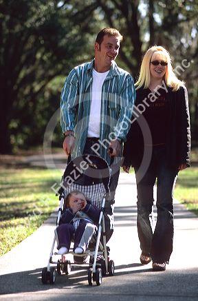 Parents walking their infant child in a stroller.  MODEL RELEASED