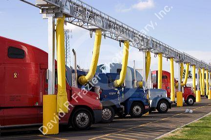 Trucks parked at a truck stop using the yellow tubes for air conditioning. Medera, California.