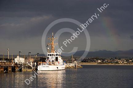Rainbow over Monterey Bay, California with Coast Guard boat in port.