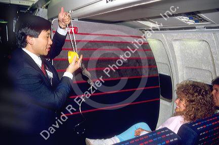 Asian male flight attendent demonstrates how to use an oxygen mask in case of emergency.